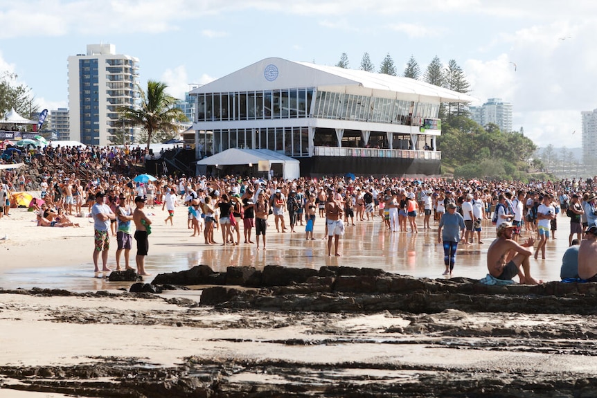 a temporary judging tower and crowd on the beach for a surfing contest