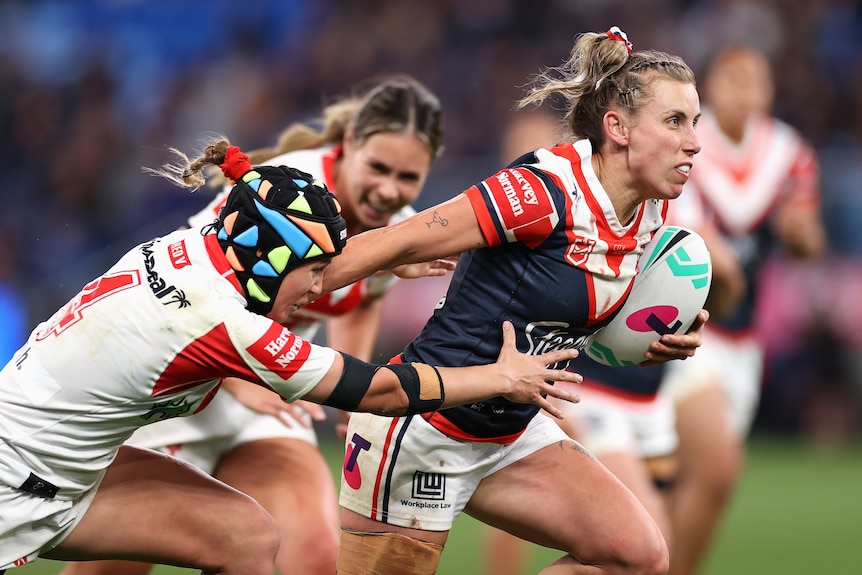 A woman evades defenders during an NRLW clash