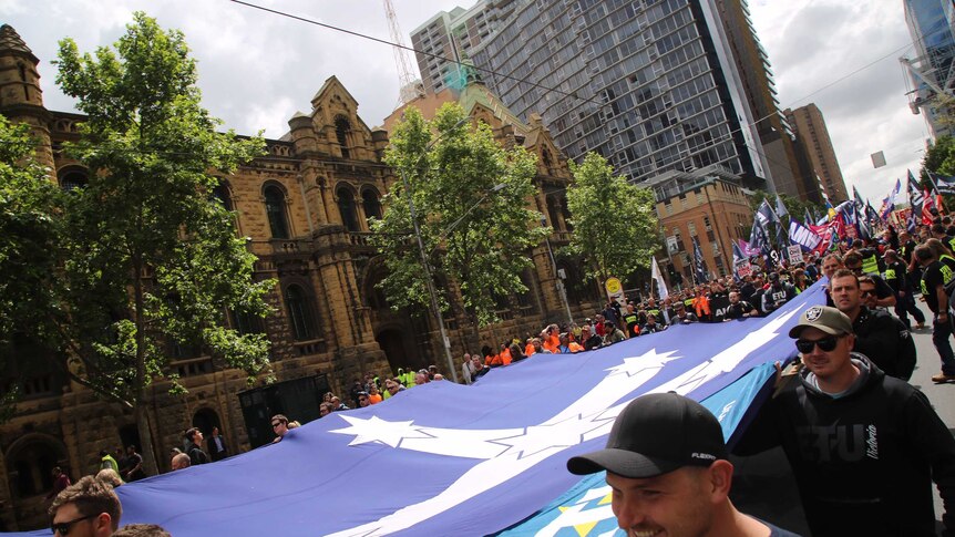 Protesters carry the Eureka Stockade flag down the middle of La Trobe Street.
