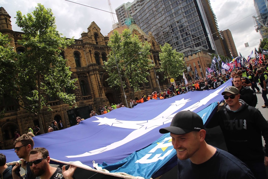 Protesters carry the Eureka Stockade flag down the middle of La Trobe Street.