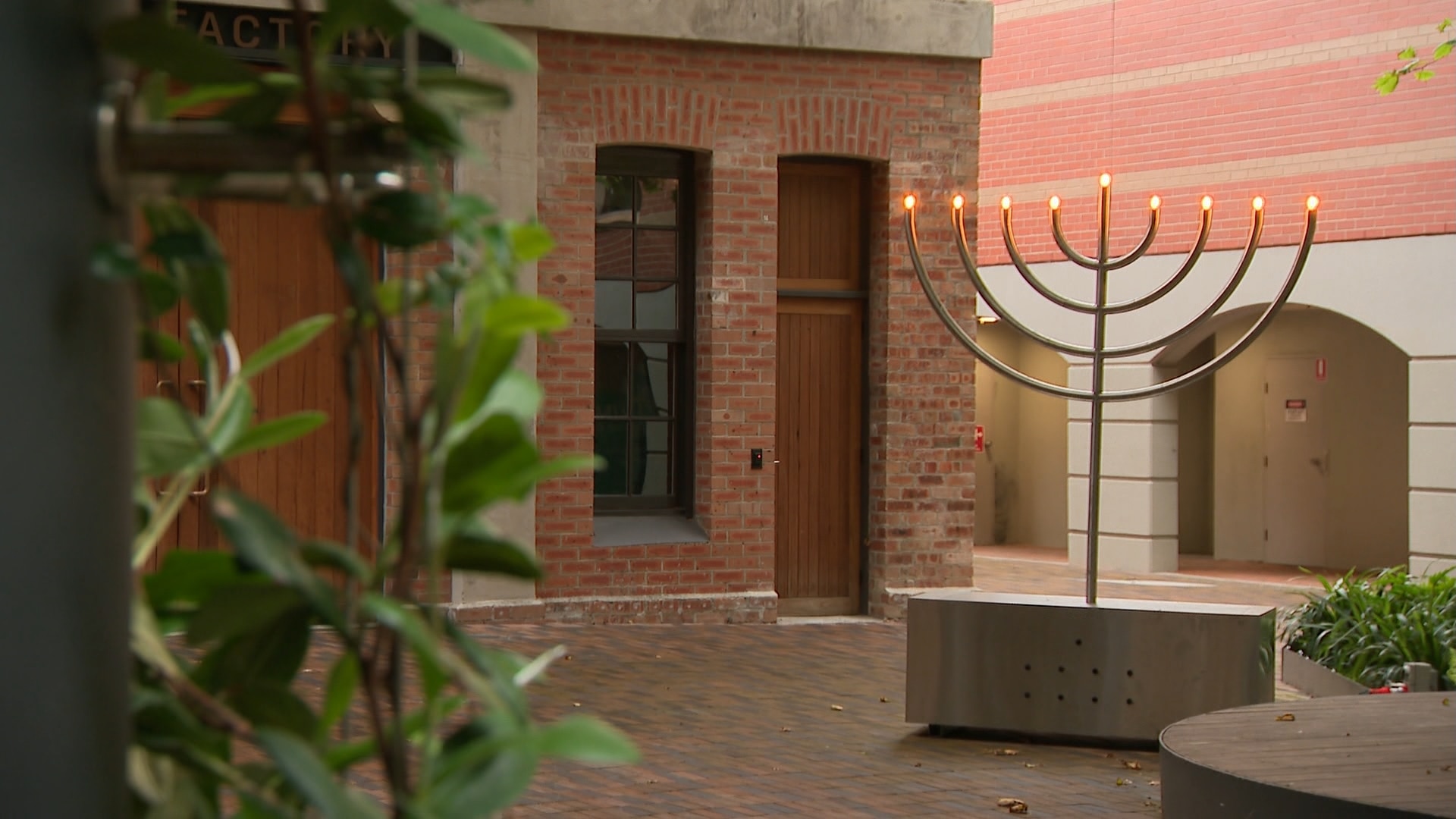 Una menorá con luces eléctricas que simbolizan velas se encuentra frente a un antiguo edificio de ladrillo donde tuvo lugar la reunión.