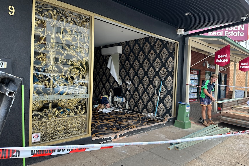 Two tradespeople are cleaning up the damage to a restaurant in Dubbo after a ute drove through the front glass window