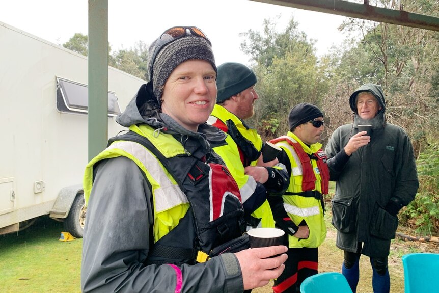 A woman wearing cold weather gear holds a cup of coffee.