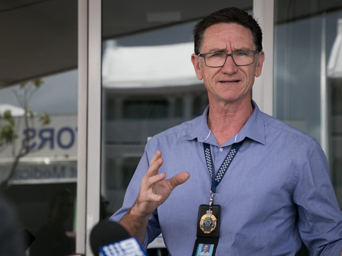 Police man talking in front of microphones at press conference.