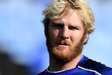 Aiden Tolman stands in a stadium wearing a blue training tshirt