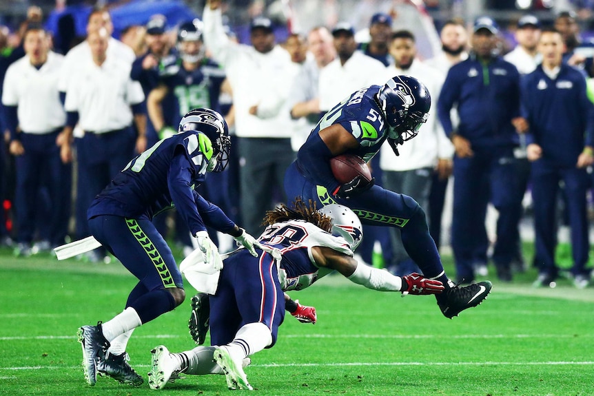 Seattle's Bobby Wagner #54 is tackled by the Patriots' Brandon Bolden #38 after his interception.