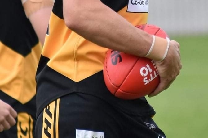 Hobart Football Club players in team colours, one carrying a ball.