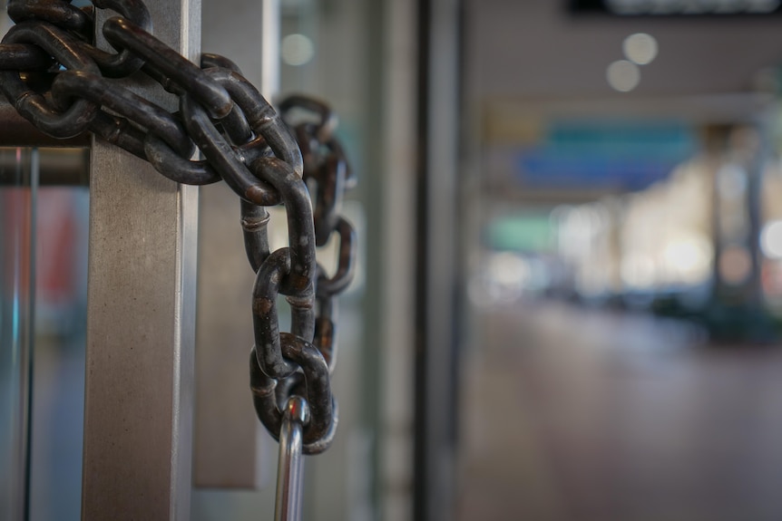 A chain and padlock on a doorway in an empty street