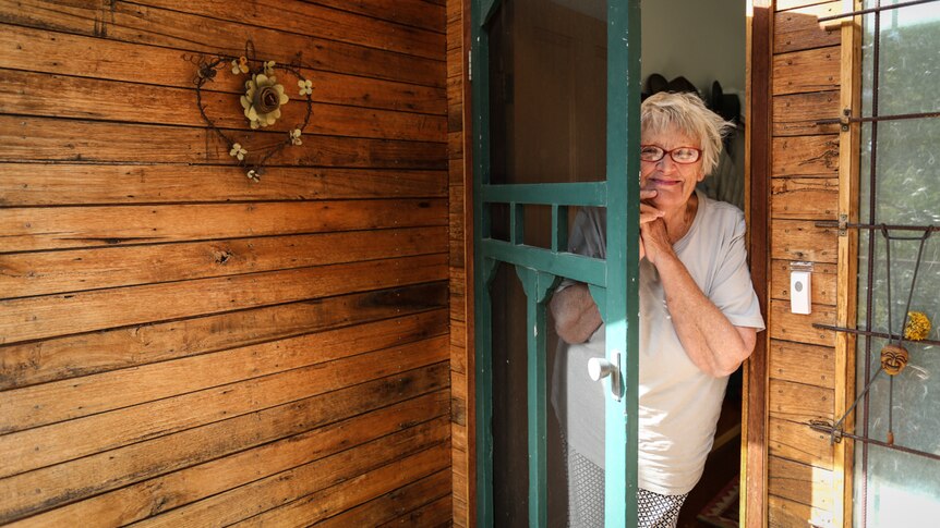 Sue Ingleton standing at her front doorway with the door slightly ajar.
