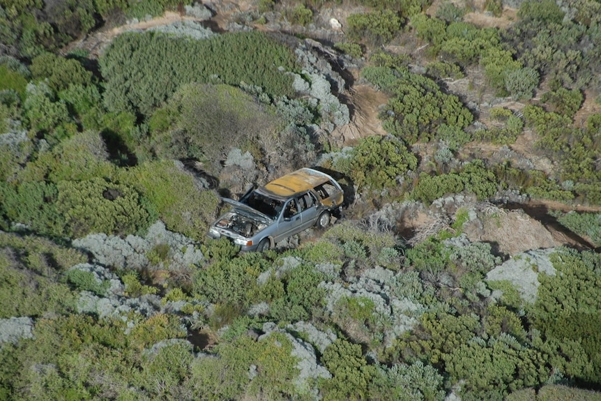 Burnt car in coastal dunes.