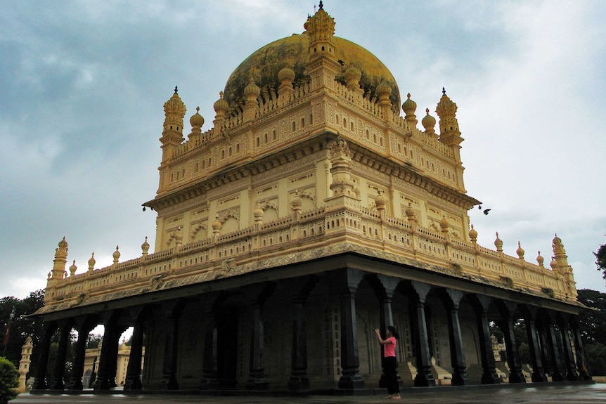 An ornate cream and black coloured mausoleum, several stories high.
