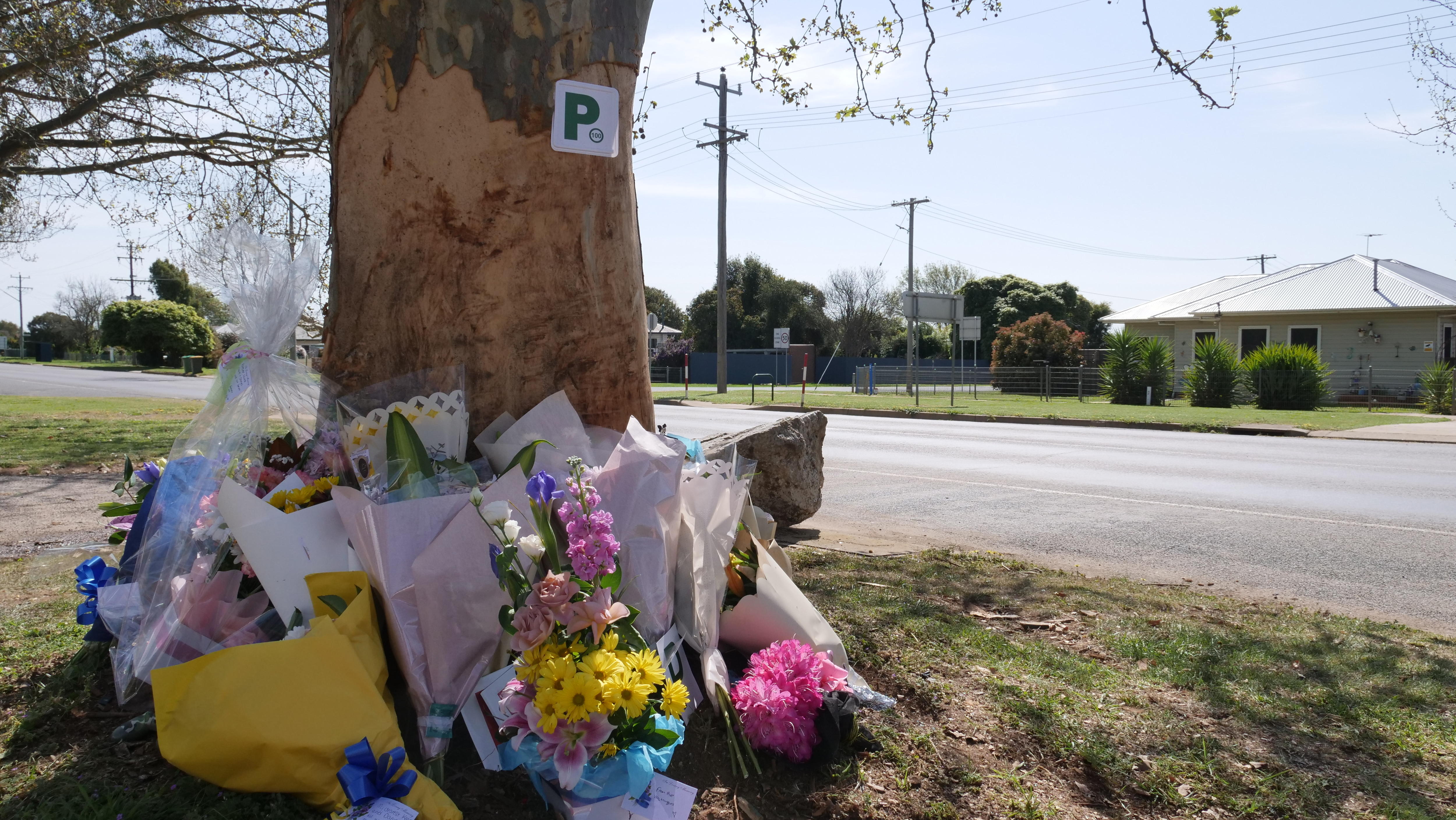 Flowers and mementos wrap around a tree base