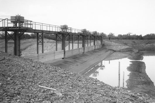 a black and white image of a metal and concrete dam