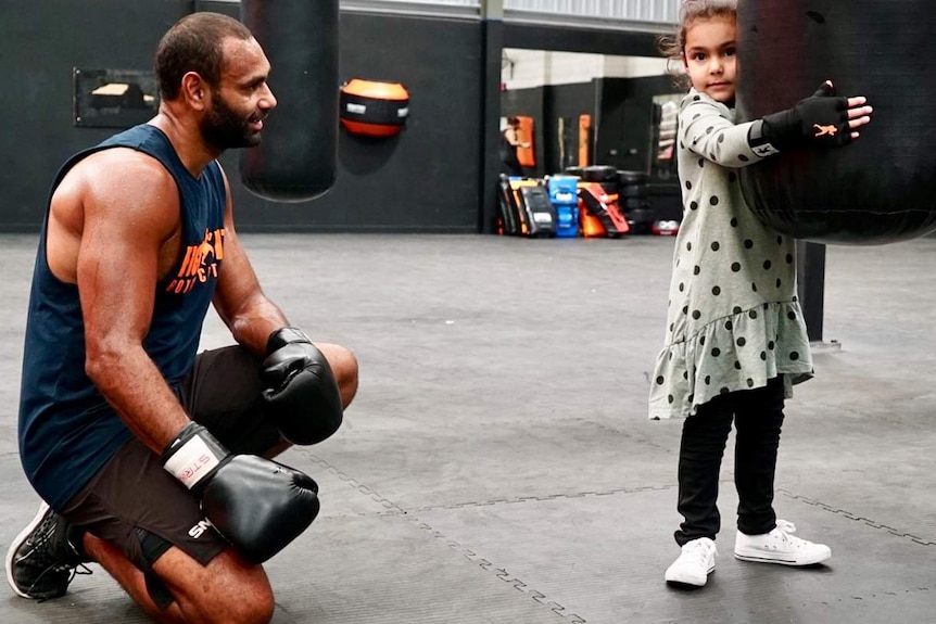 Travis Varcoe watches daughter Frankie hold a boxing bag.
