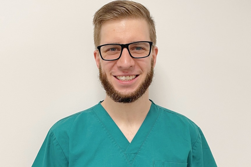 A man in green scrubs and glasses