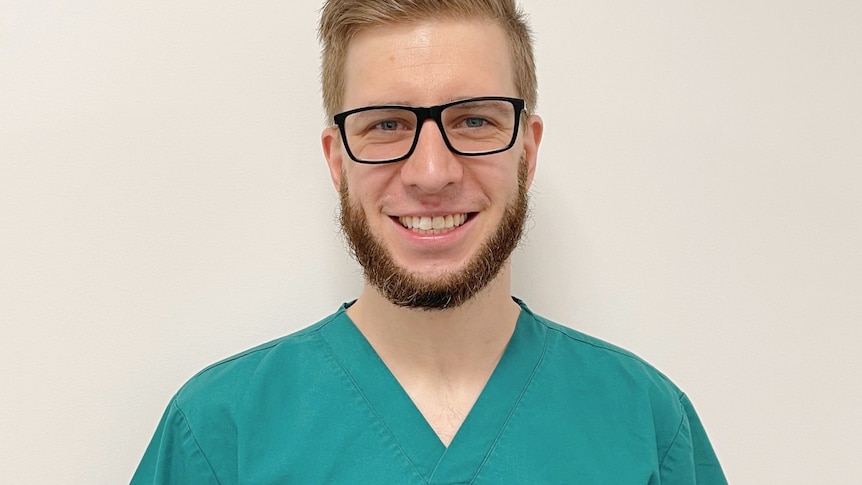 A man in green scrubs and glasses