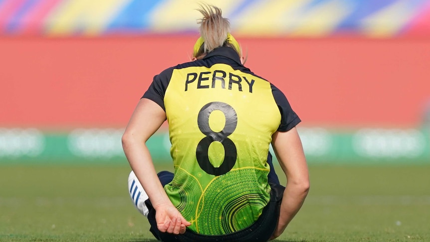 Ellyse Perry's name and number is visible on the back of her Australian jersey as she sits on the ground after being injured.