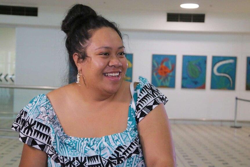 A woman in a blue dress smiles.