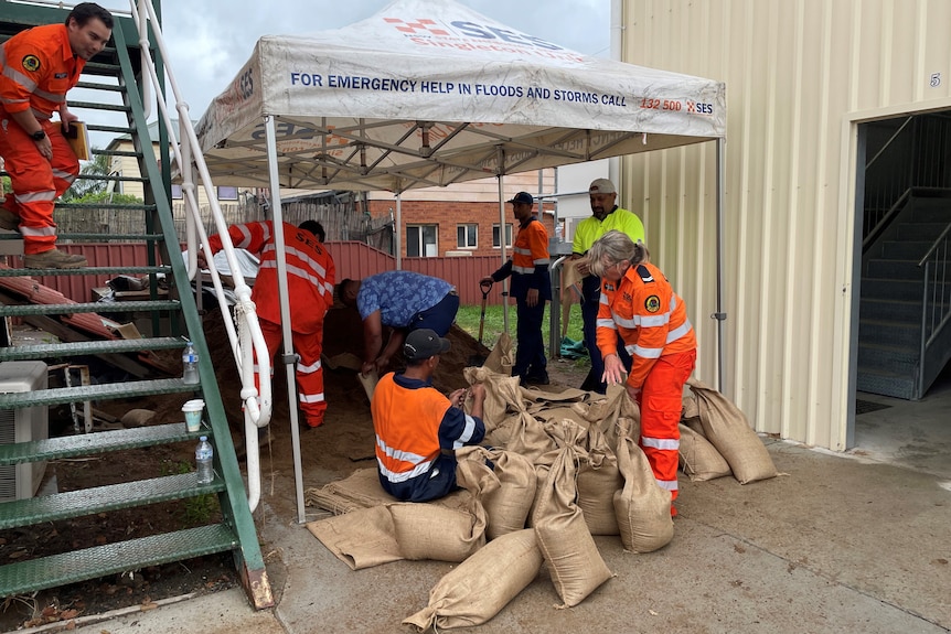 People in SES uniforms fill sandbags.