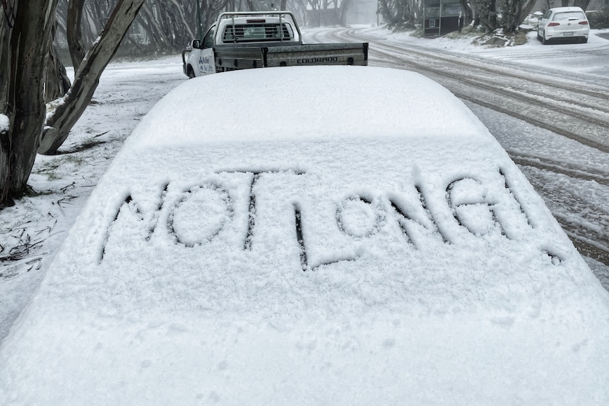 Car windscreen with the words Not Long written in snow. 