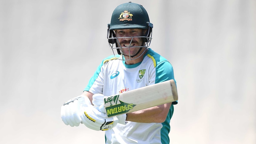 A helmet-wearing batsman smiles as he stands padded up in his training gear ahead of a Test match.