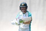 A helmet-wearing batsman smiles as he stands padded up in his training gear ahead of a Test match.