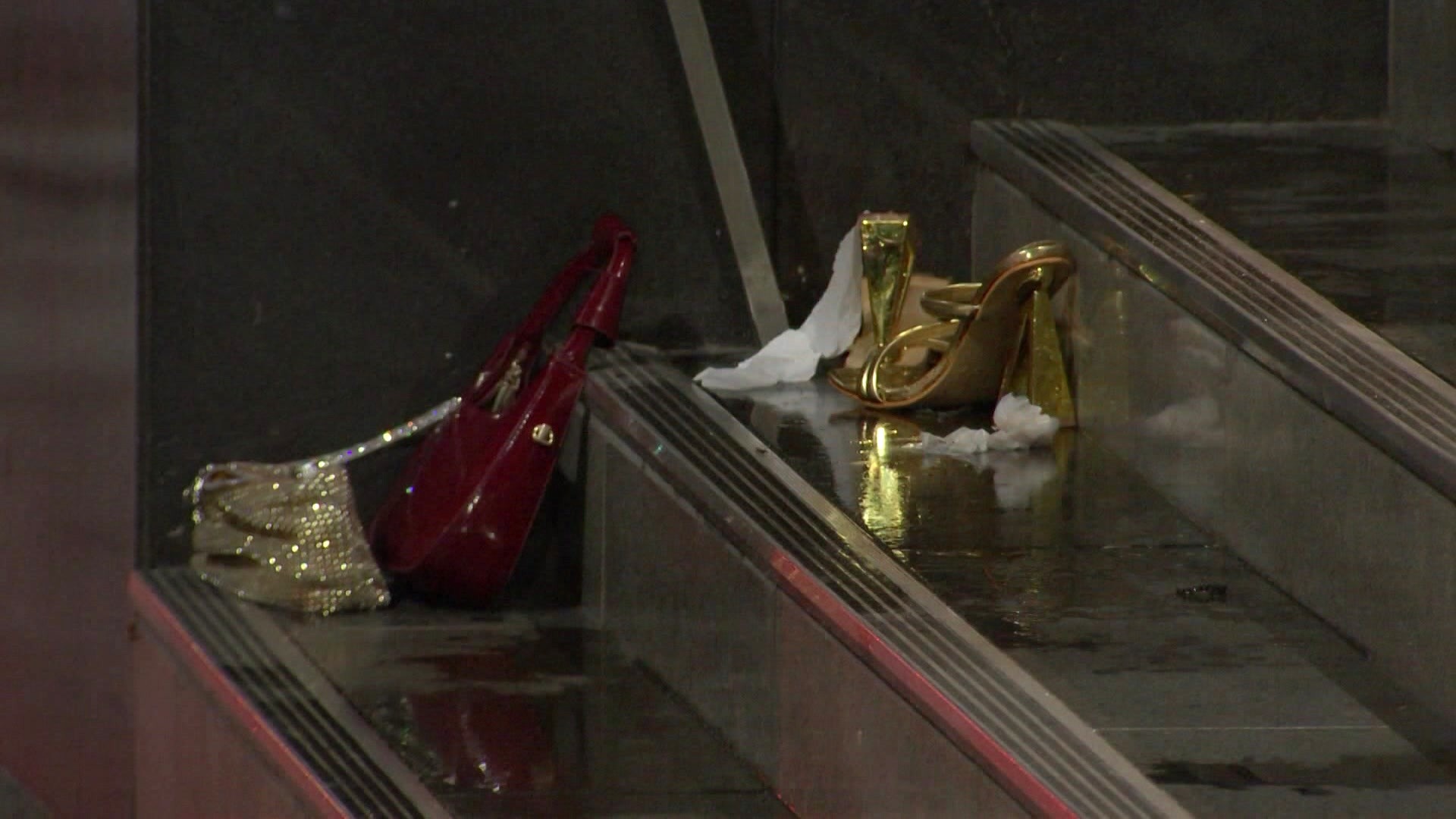 Un bolso de lentejuelas y un bolso rojo se encuentran en las escaleras por la noche junto a un par de tacones dorados y pañuelos.