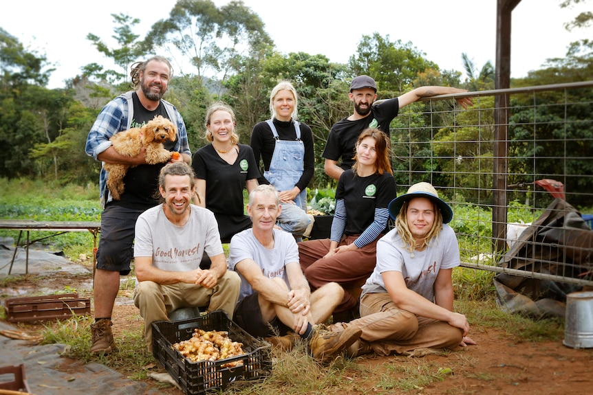 Eight people sit and stand at an organics farm