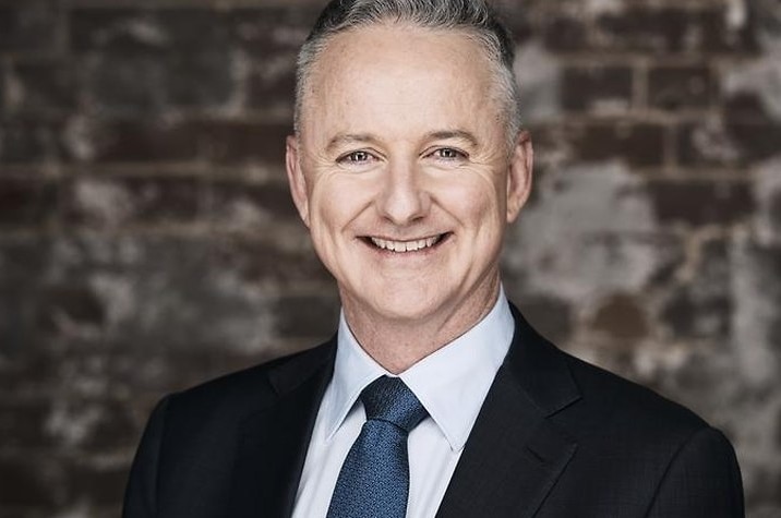 Hugh Marks smiles while wearing a suit