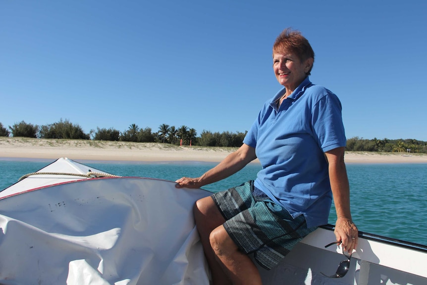 A woman in a blue shirt sits at the front of a small boat.