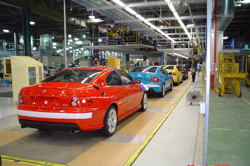 Three cars lined up on a conveyor belt 