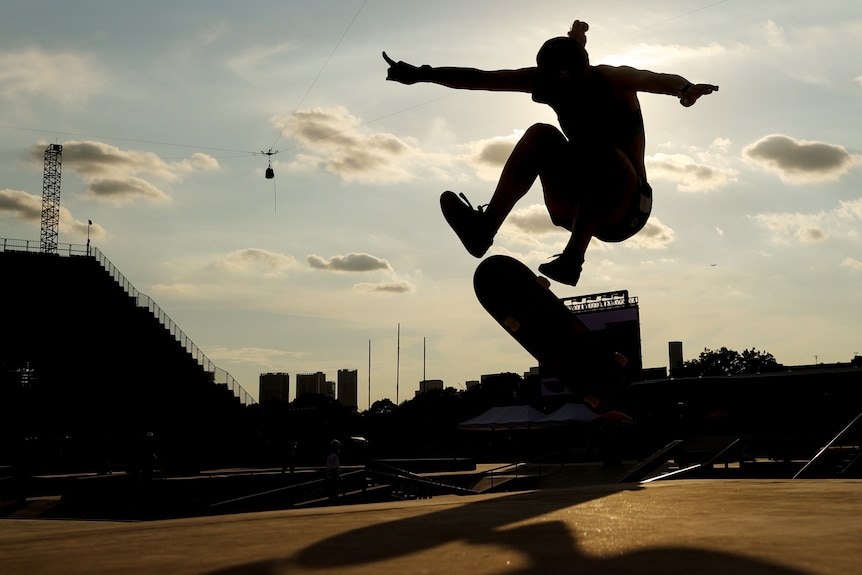a skateboarder performs a trick in silhouette
