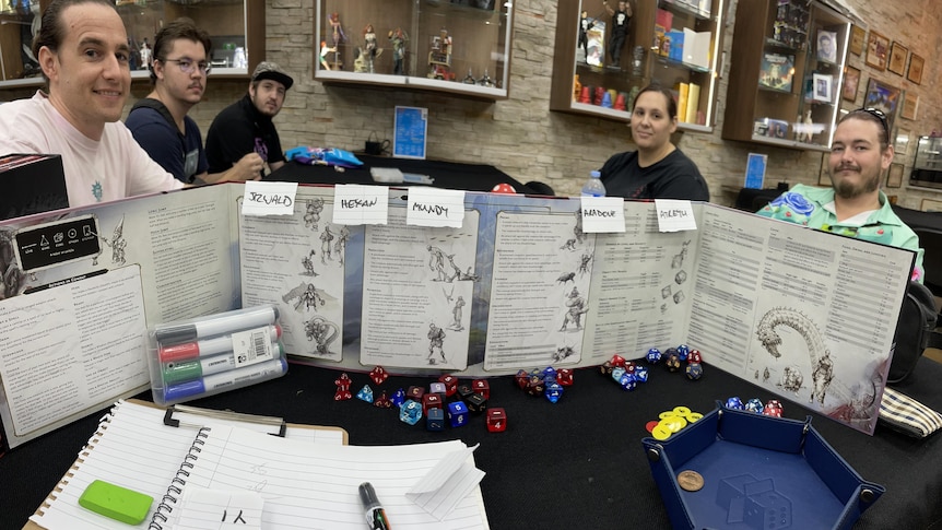 Five players sit around a table playing Dungeons and Dragons.