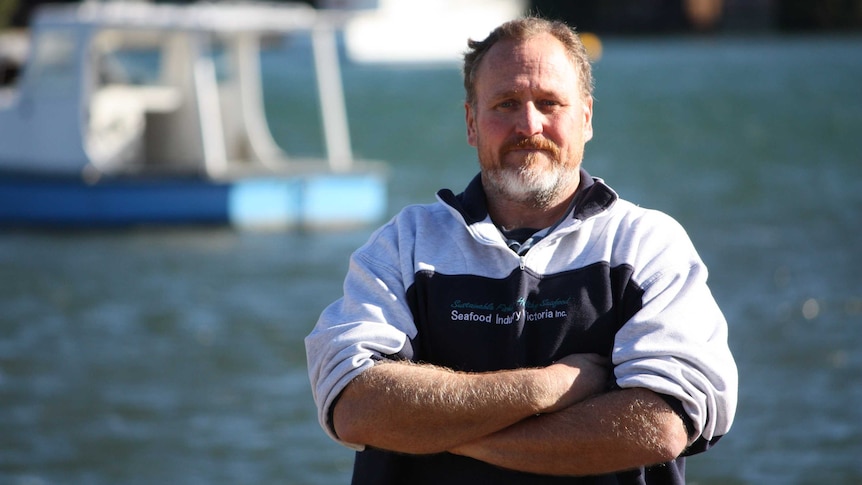 Garry Leonard pictured with arms folded near boats on the Gippsland Lakes.