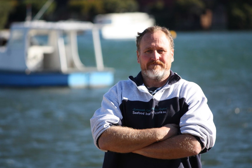 Garry Leonard pictured with arms folded near boats on the Gippsland Lakes.
