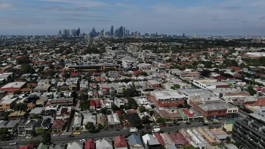 An aerial image of Melbourne showing city skyscrapers in the distance and suburbs in the foreground.