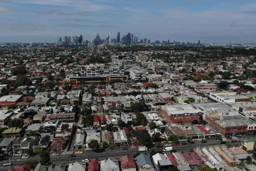 An aerial image of Melbourne showing city skyscrapers in the distance and suburbs in the foreground.