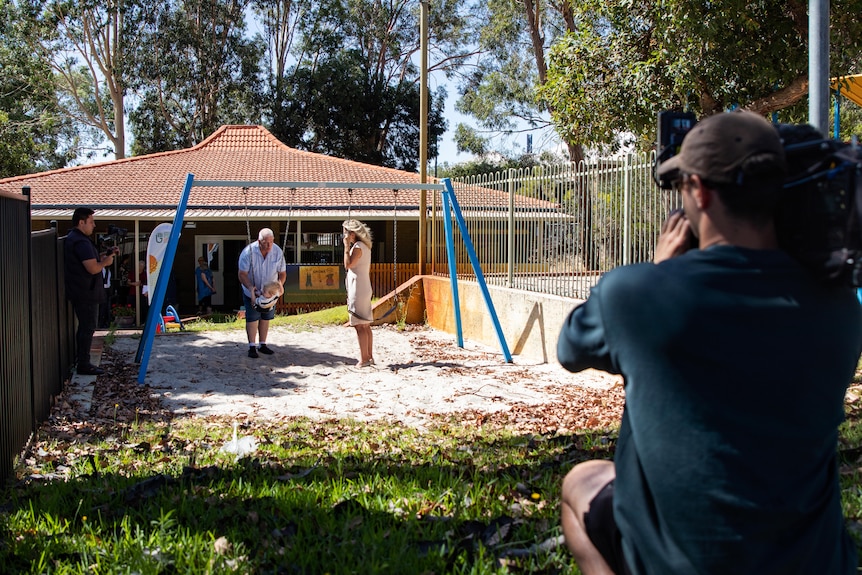 A woman standing in a playground being filmed by people holding cameras