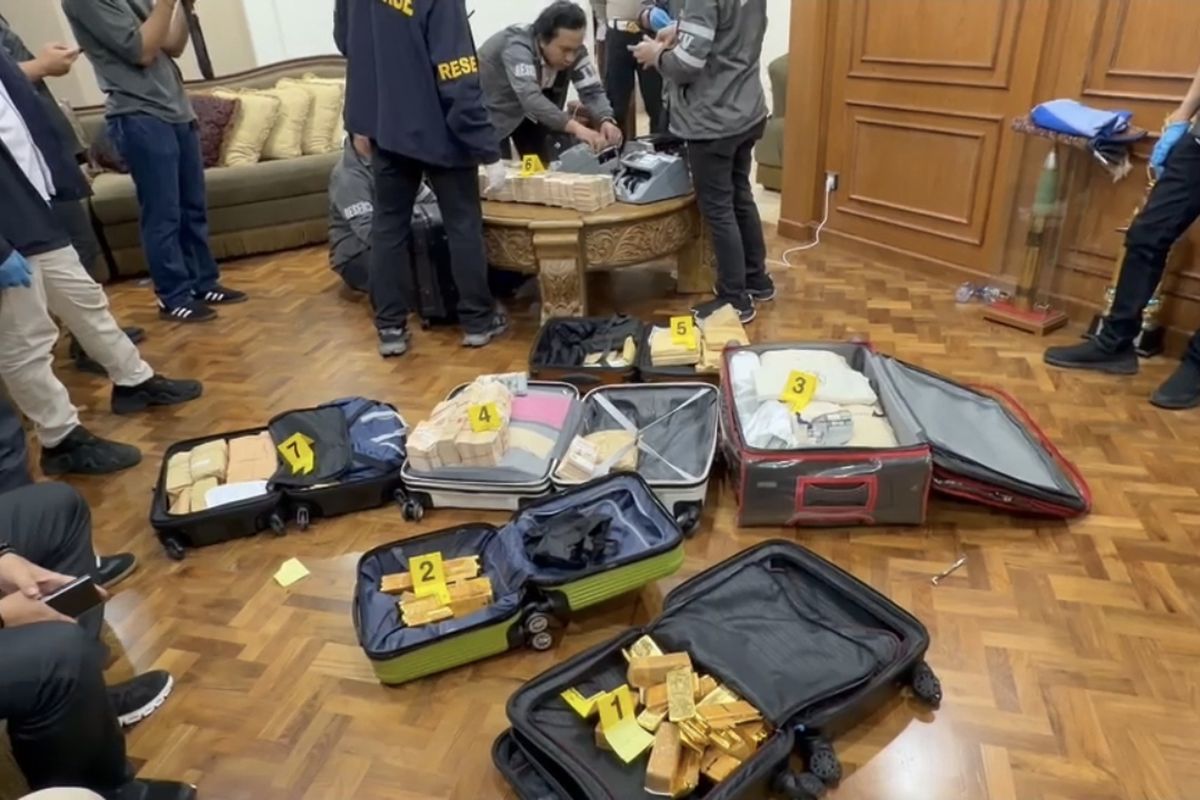 Six suitcases containing gold and cash laid out on the floor.