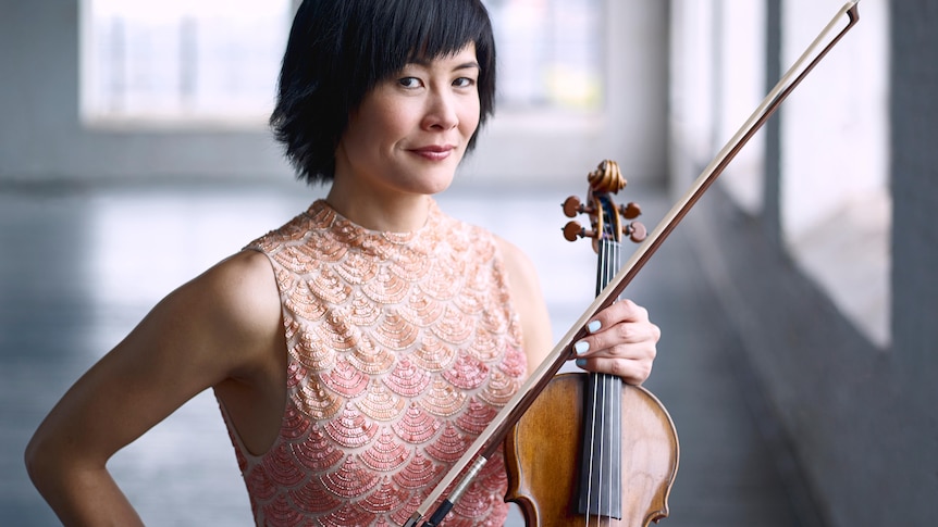 Violinist Jennifer Koh stands holding her violin