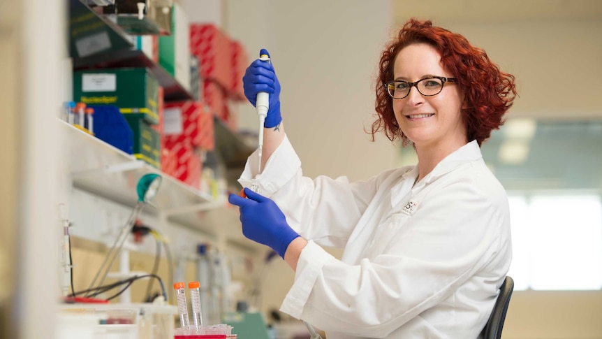 Dr Jemma Evans holds a pipette and test tube in her laboratory.