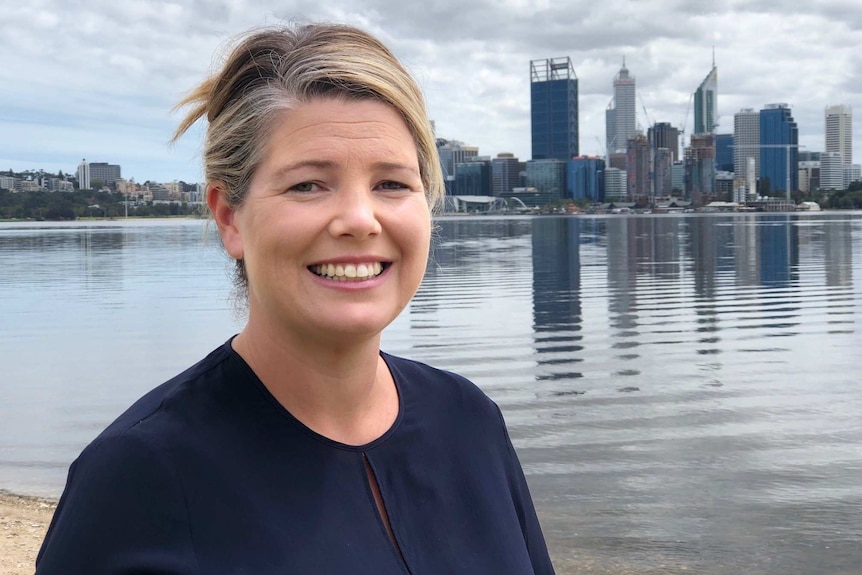 Dr Amanda Davies stands in front of the Perth syline.