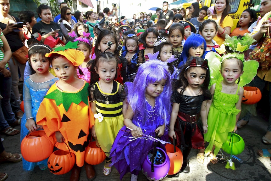 Dozens of children wear various Halloween costumes as part of a parade