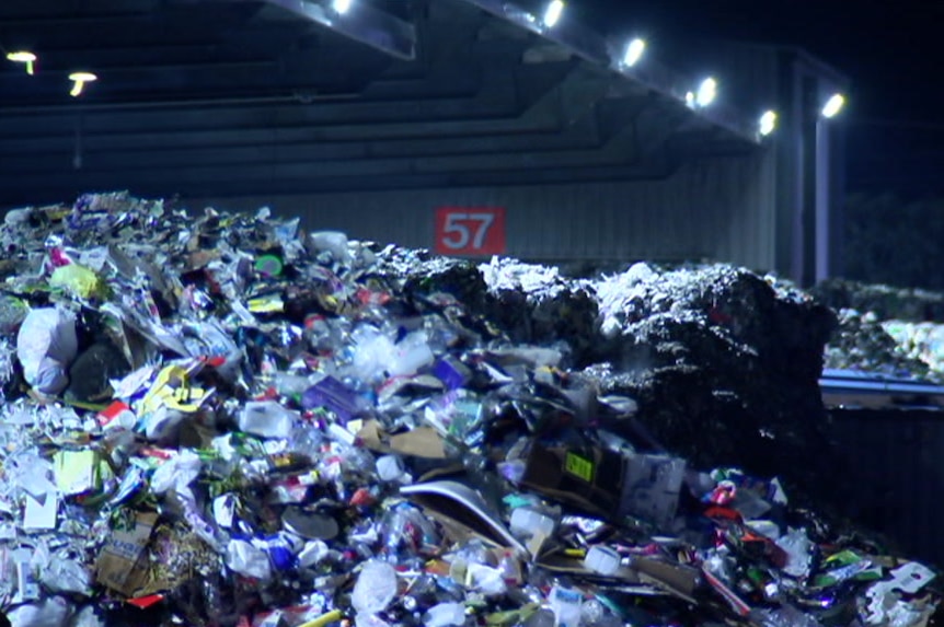 A large pile of plastic recycling materials sits on the ground.