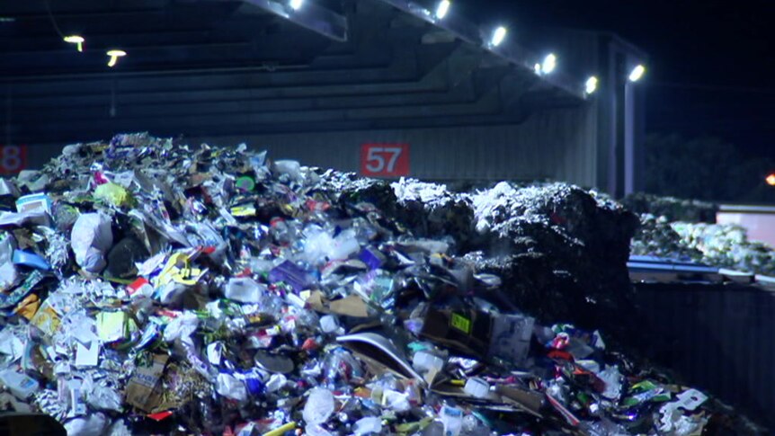 A large pile of plastic recycling materials sits on the ground.