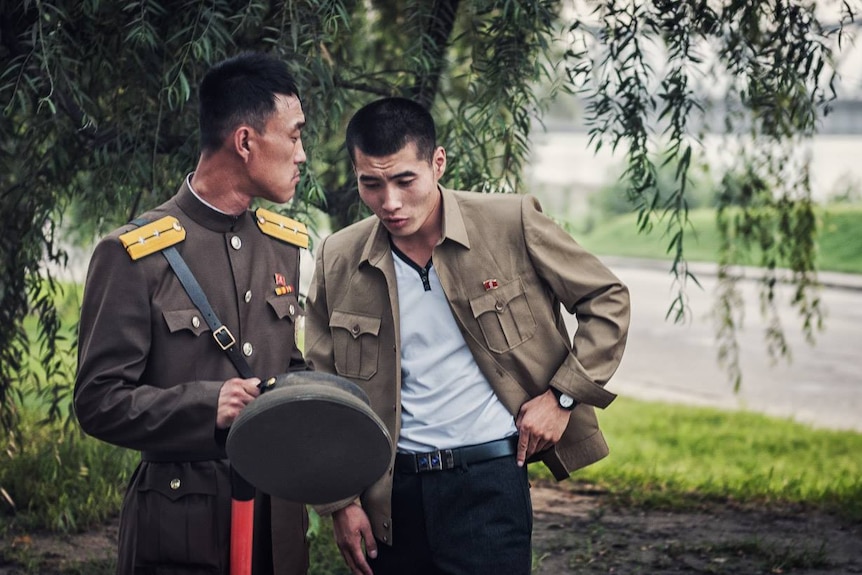 Two North Korean soldiers confer outdoors.