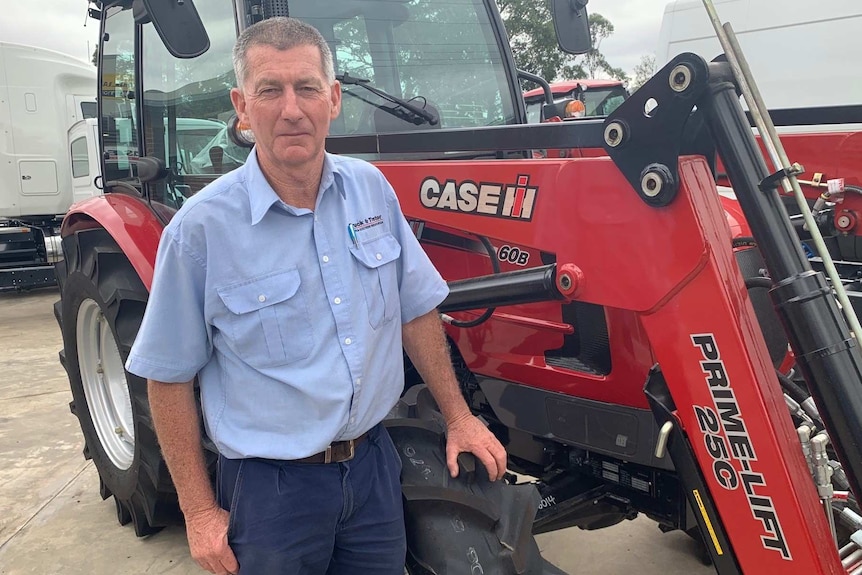 Agricultural machinery salesman Ron Arthur stands in front of a tractor