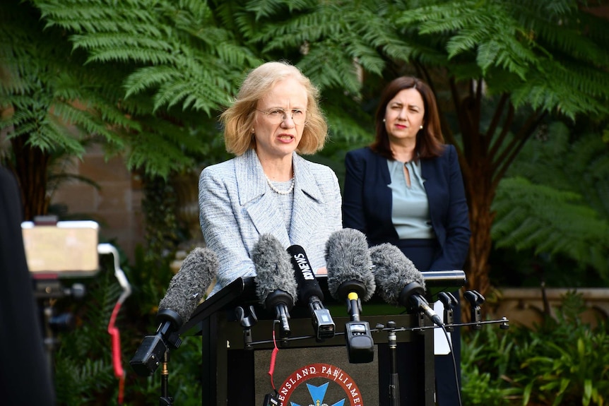 Dr Jeanette Young speaks in front of microphones.