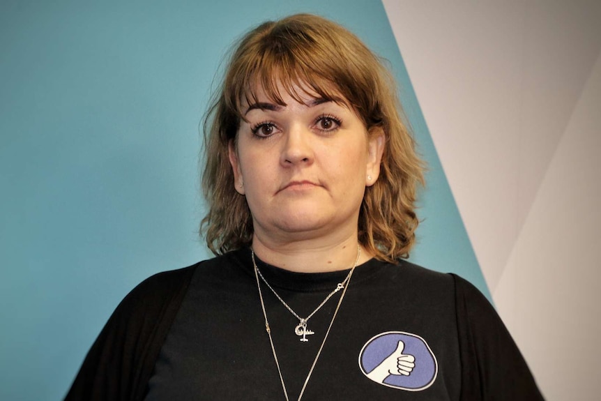 A woman wearing a black shirt and a necklace poses for a photo