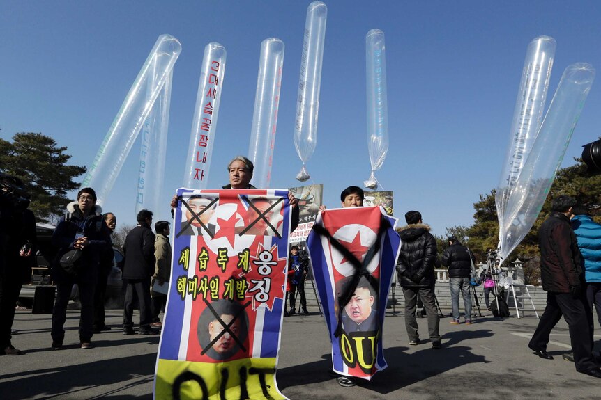 Park Sang Hak and a South Korean activist hold North Korean flags with defaced pictures of leader Kim Jong Un.
